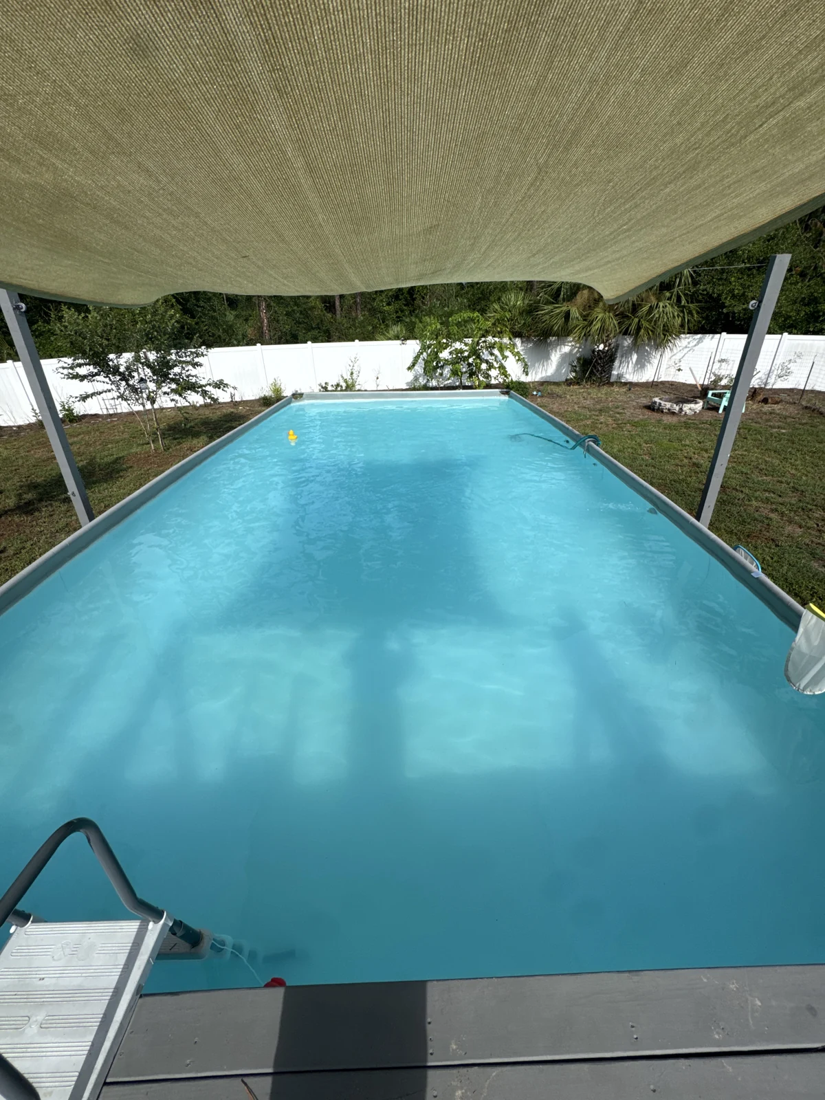 An above-ground pool under a shade sail