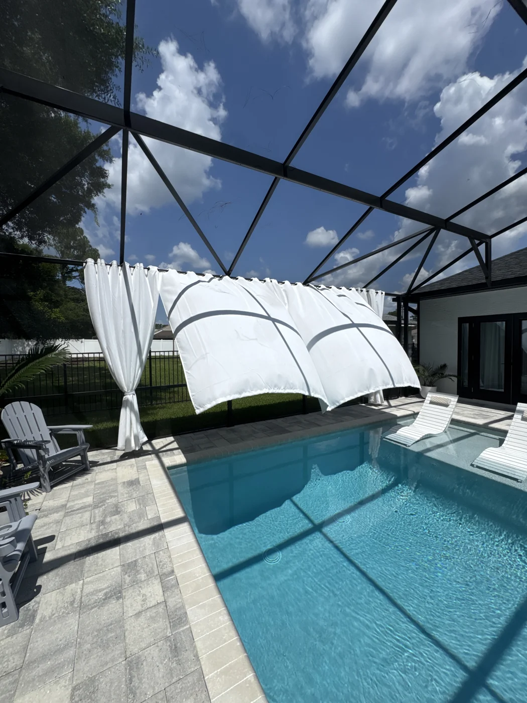A modern pool and sun shelf beside a screened patio